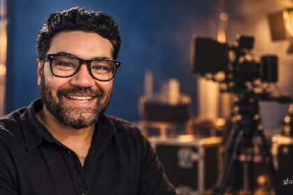 Albert Omstead mit Brille vor einem redaktionell gestalteten Filmstudiohintergrund